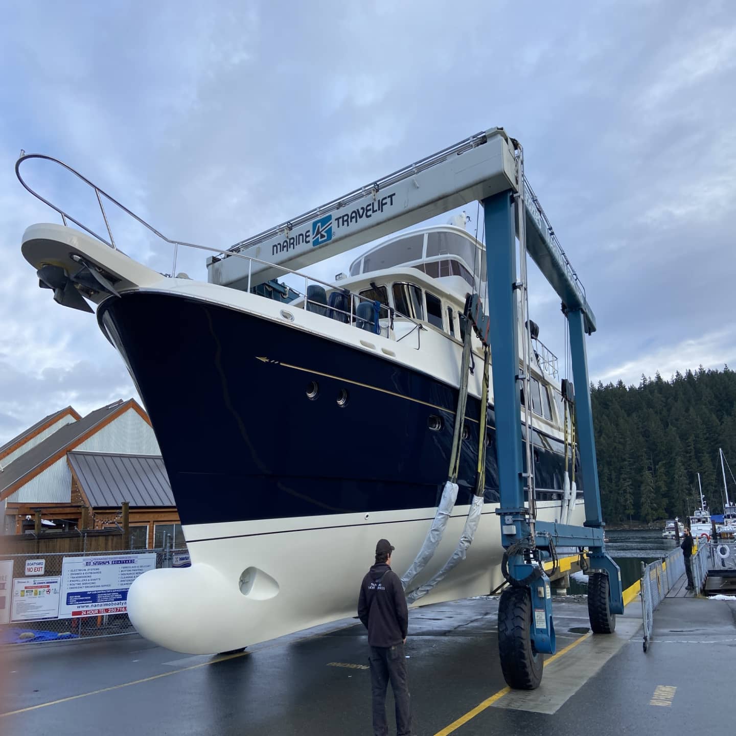 big yacht lifted on pier with crew working on it